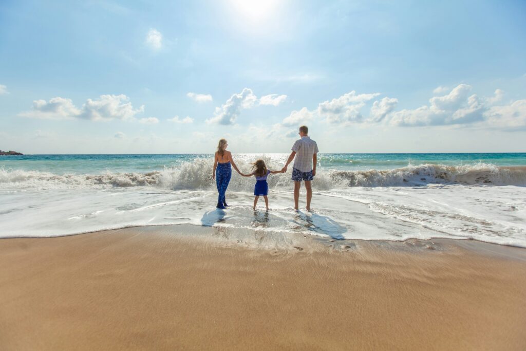 A couple with their child standing in the surf of a St John beach.